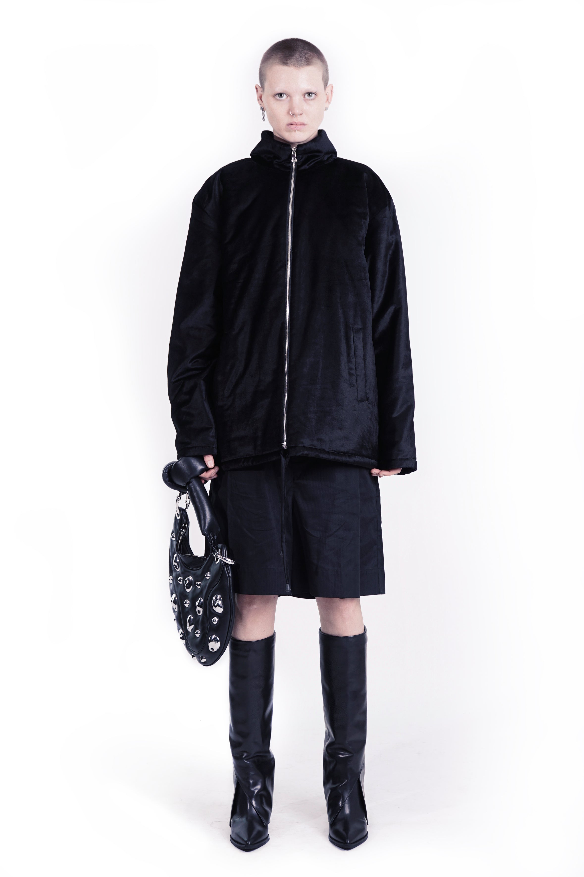 Model wearing PMP152 adddress black tailored wide shorts with structured pleats and knee-high boots